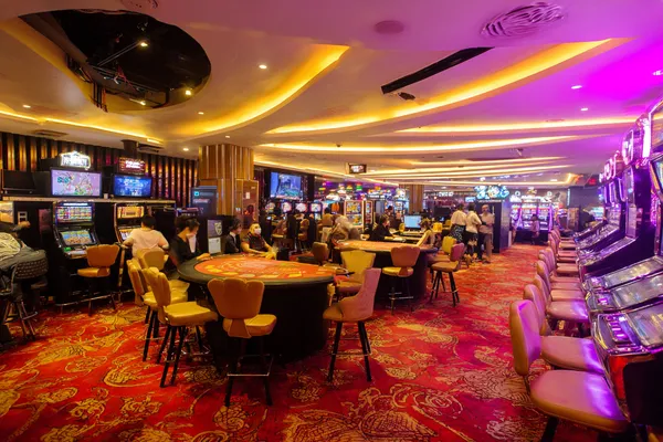 A young woman relaxing with her phone while dynamic casino elements float around her, illustrating the smooth mobile experience offered by the JILIDD app.